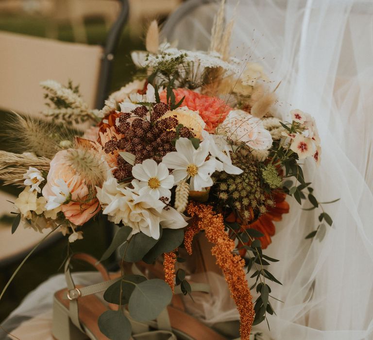 Mixed summer wedding bouquet with white, orange and green florals next to green block heel wedding shoes with bow detail