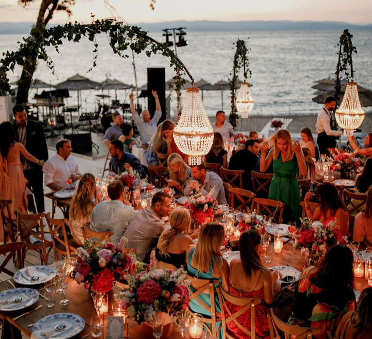 Wedding guests sit outdoors for Greece wedding at beach bar 