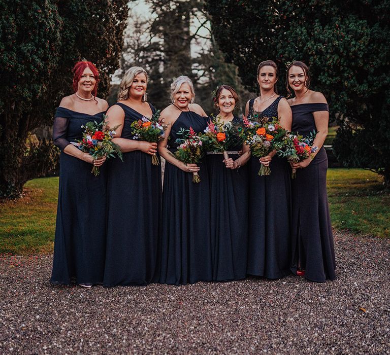 Bridesmaids in dark blue dresses in various types with bright wedding bouquets 