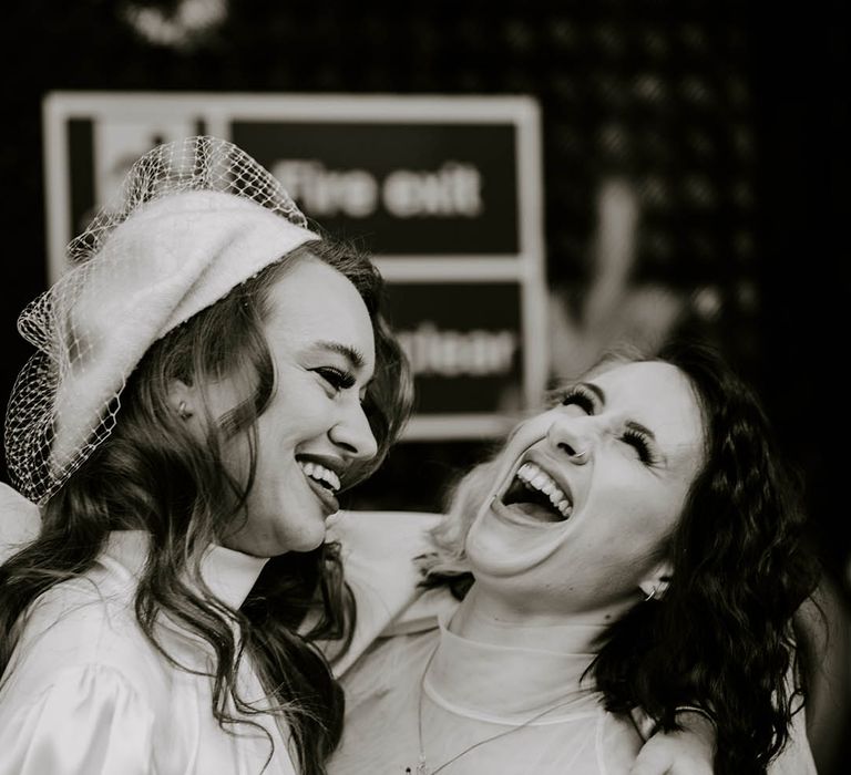 LGBTQI couple laughing in high neck wedding dresses 