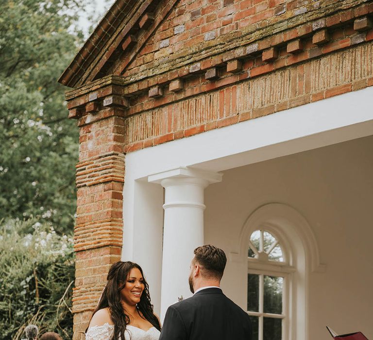 Bride and groom hold hands at their outdoor wedding ceremony 