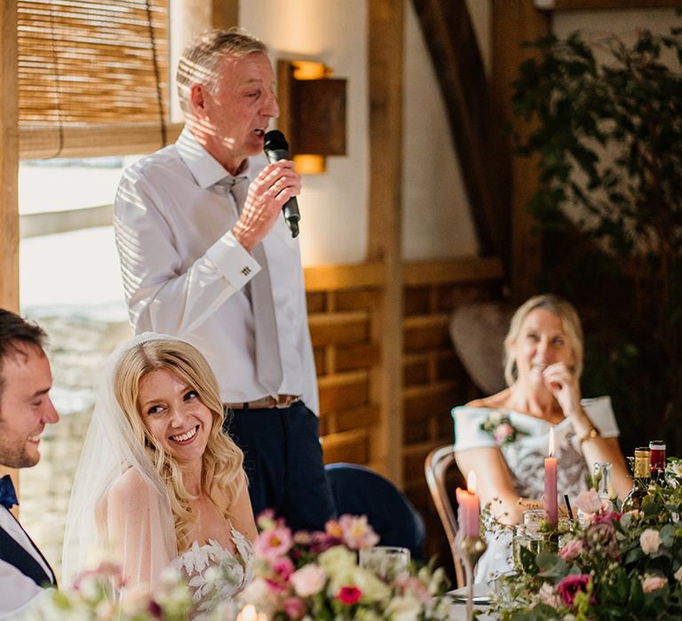 Bride and groom laugh as the father of the bride reads out his speech