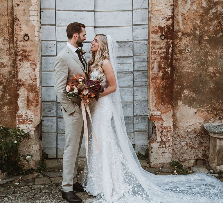 Bride wears Emmy Mae Bridal wedding dress and looks lovingly at her groom in stone beige three piece suit with green wool tie