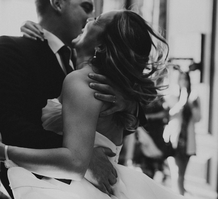 Bride & groom laugh during first dance in black & white image 