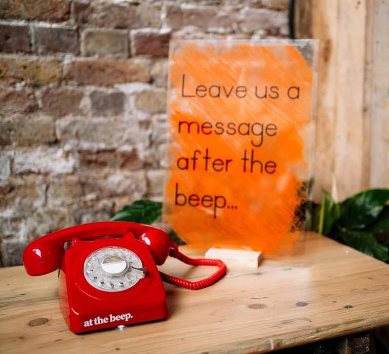 Vintage red phone on wooden table beside orange sign for alternative guest book idea