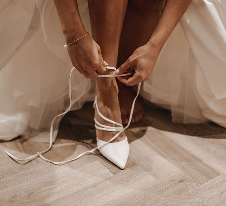 Bride wears white pointed heels complete with lace up ties 