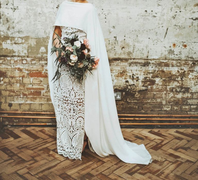 Bride in a boho lace wedding dress with a plain white cape covering 