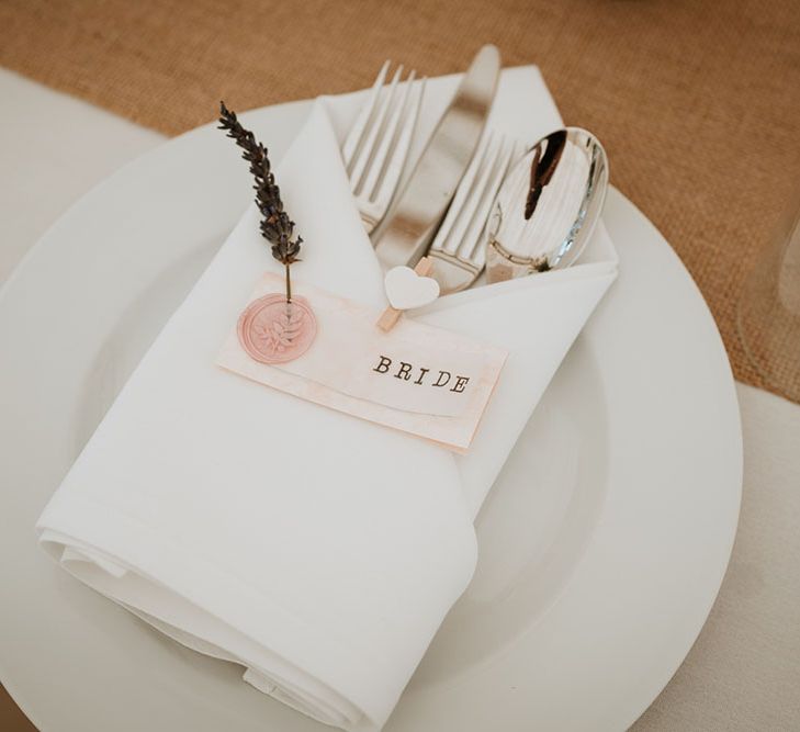 White fabric napkin complete with pale pink place name cards and delicate foliage decor 