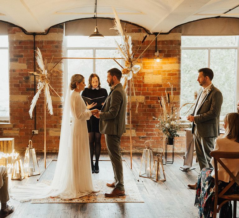 Bride & groom marry at the Venue Bowers Mill in front of brass arch complete with pampas grass decor 