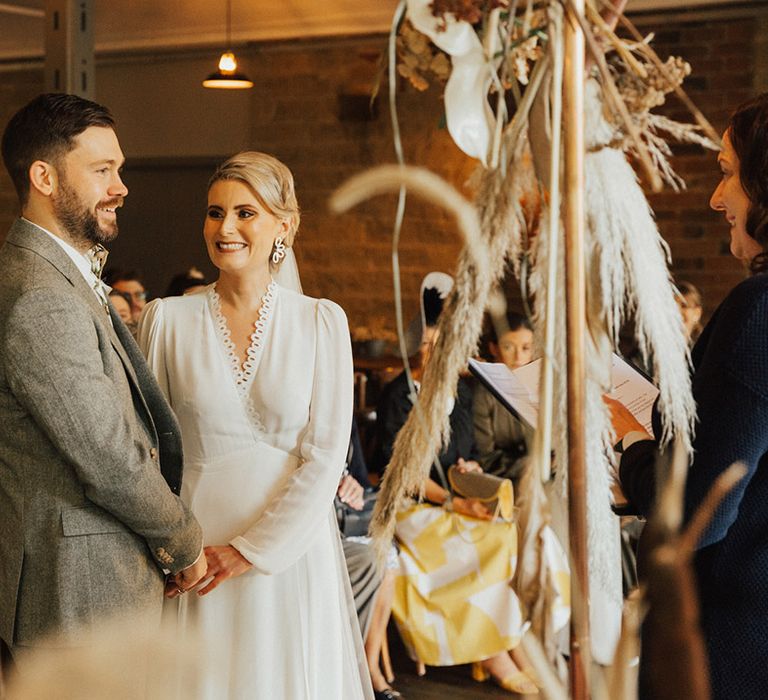 Bride wears long sleeve Reformation wedding dress with scalloped lace edge detailing 