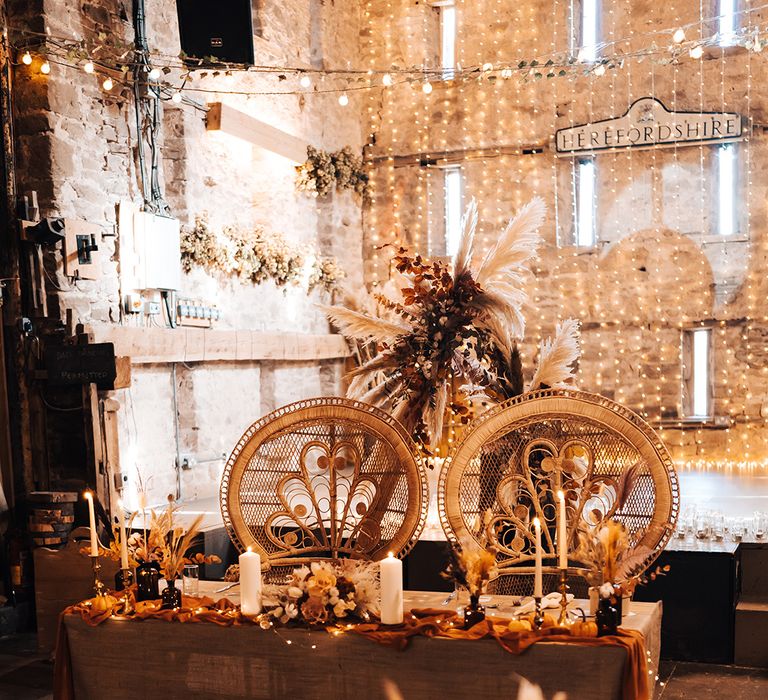 Sweetheart table complete with hessian tablecloth and burnt orange fabric table runner surrounded by fairy light canopy 