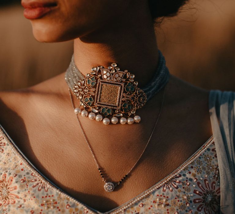 Indian bride wears choker styled statement necklace with pearl embellishment 