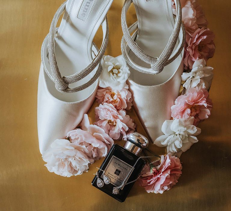 White satin pointed wedding shoes with the bride's Jo Malone perfume and silver jewellery 