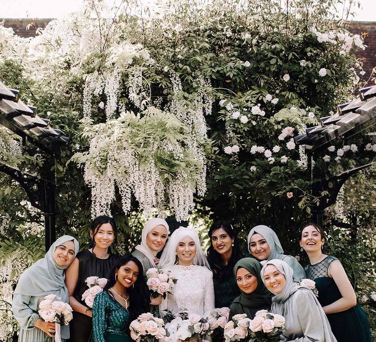 Muslim bride smiling with her bridesmaids in mismatched shades of green and styles 