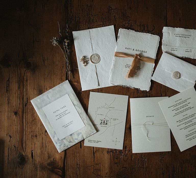 White classic wedding stationery tied with silk ribbon complete with typewriter style and personalised stamps on wooden table 