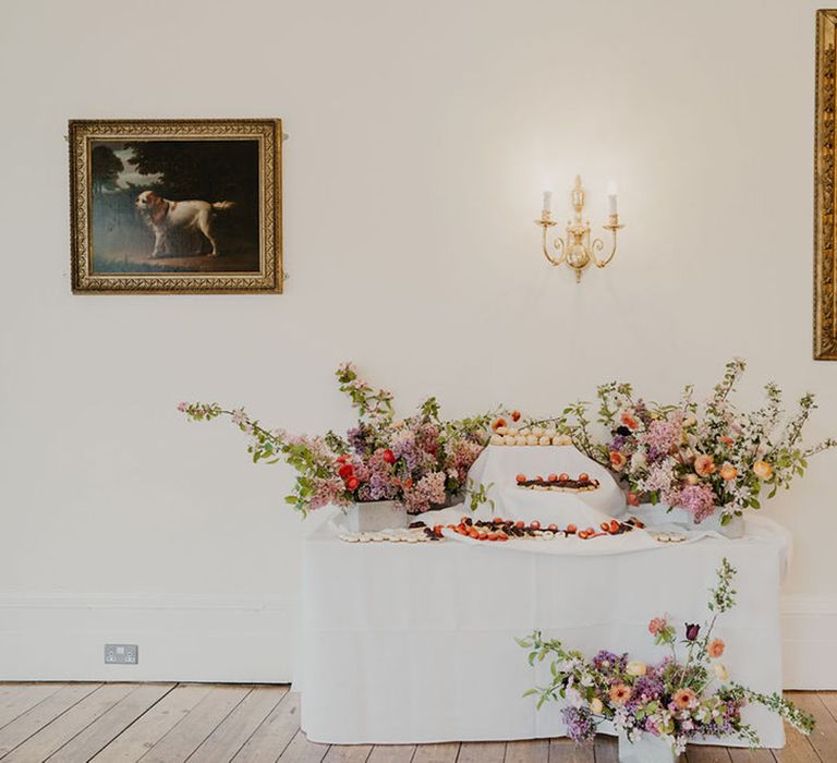 Brightly coloured florals surrounded dessert table 