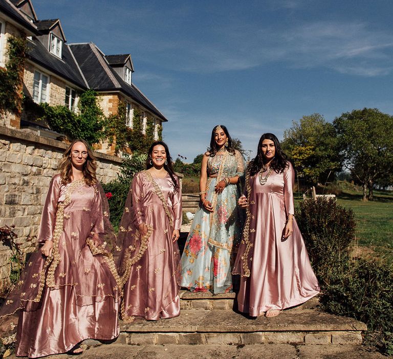 Bridesmaids wear satin pink bridesmaid dresses complete with gold edged sash  