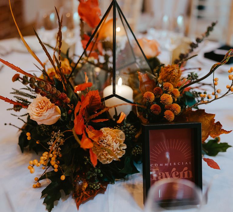 Autumnal floral arrangements surround industrial styled lanterns with white pillar candles 