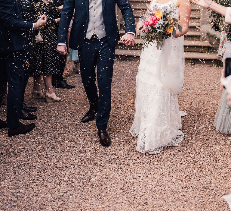 The bride and groom smile at each other for their confetti exit moment at their country house wedding venue 