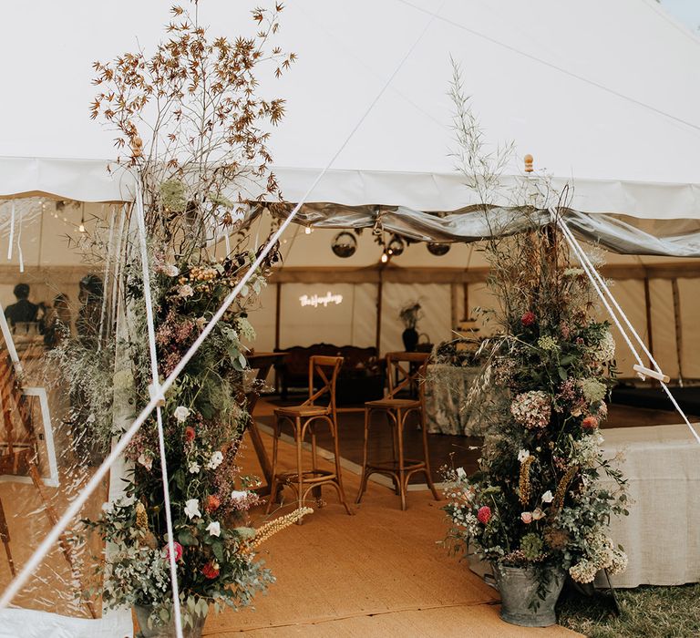 The marquee at Duddon Mill Farm with flower column entrance flower decorations and a neon sign 