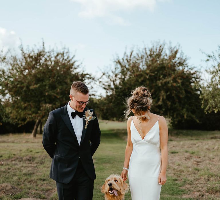 The bride and groom pose with their pet dog, Herman who sticks out his tongue 