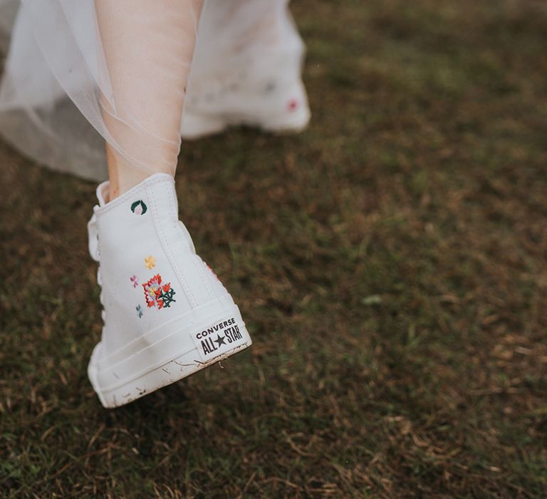 Bride wearing white wedding trainers with embroidered flowers 