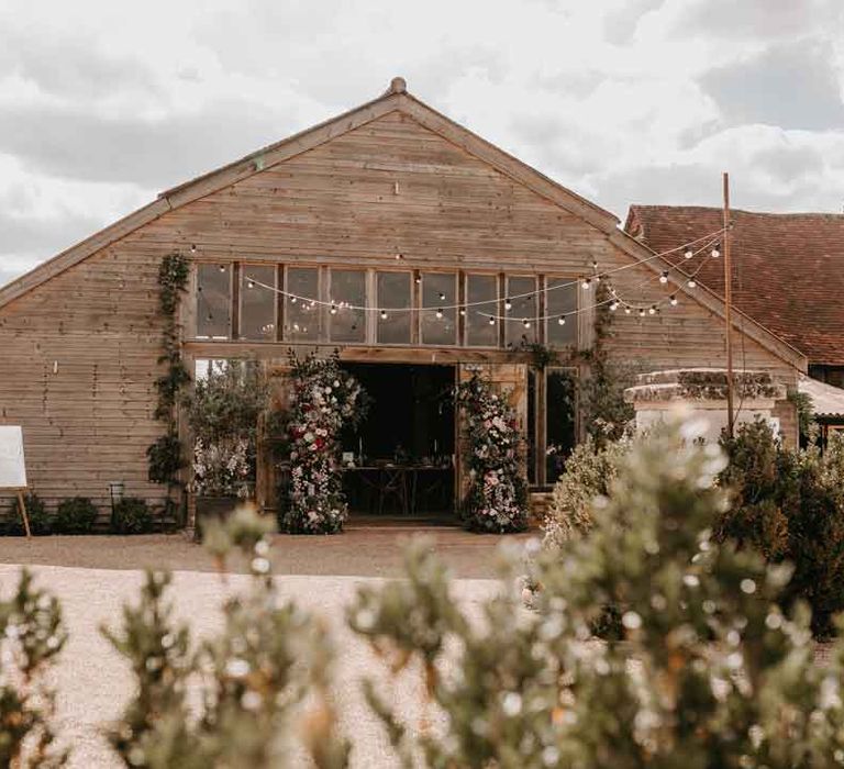 Exterior of High Billinghurst Farm with fairy lights and open doors for Gujarati wedding ceremony 