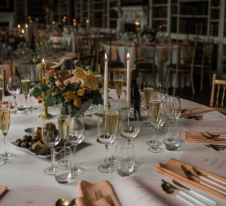 Romantic candlelit wedding breakfast in the library of St Giles House with orange autumnal wedding table centrepieces 