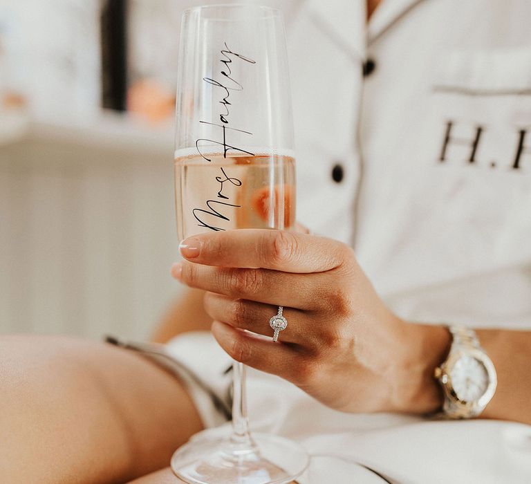 Bride with personalised champagne glass with a pavé engagement ring and a white and gold watch for wedding day 