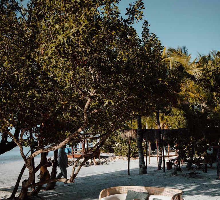 Cream love seat, two wooden stools and wooden chair wedding furniture on destination beach wedding 