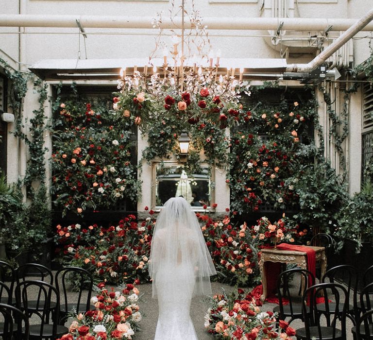 Bride in stunning mermaid bridal gown surrounded by incredible wedding flower arrangements 