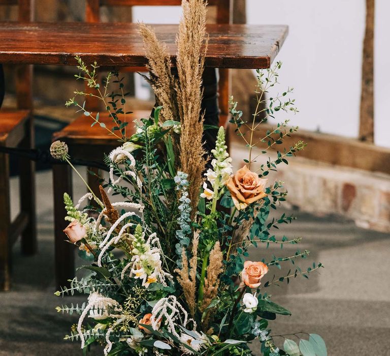 Pampas grass, eucalyptus, blush garden roses, dried flowers and foliage aisle flower arrangements at South Farm wedding venue