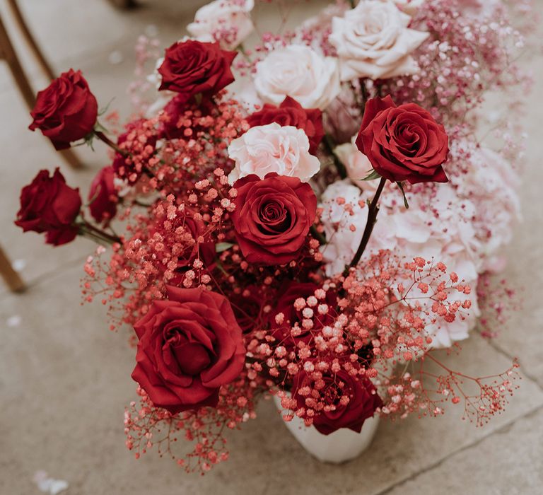 Red and pink wedding flowers decorating the aisle with roses and gypsophila 