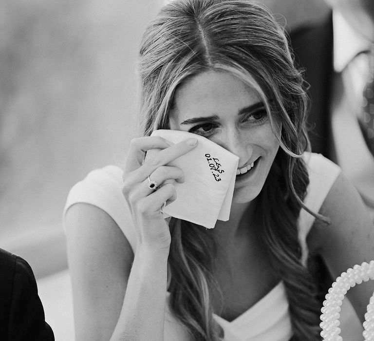 bride wiping her tears with an embroidered handkerchief during the wedding reception speeches 