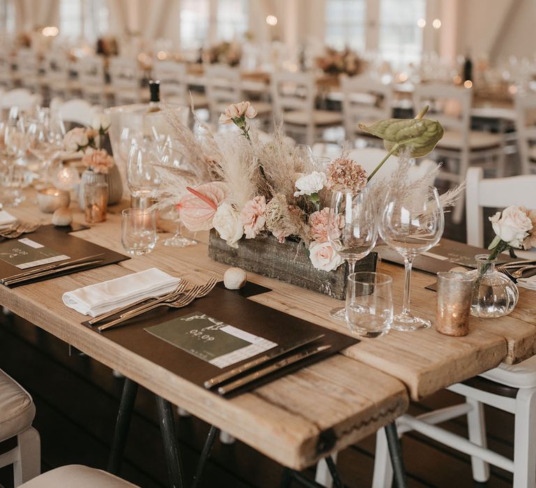 place setting with black place mat, and boho flower arrangement in a box including pampas grass and anthuriums