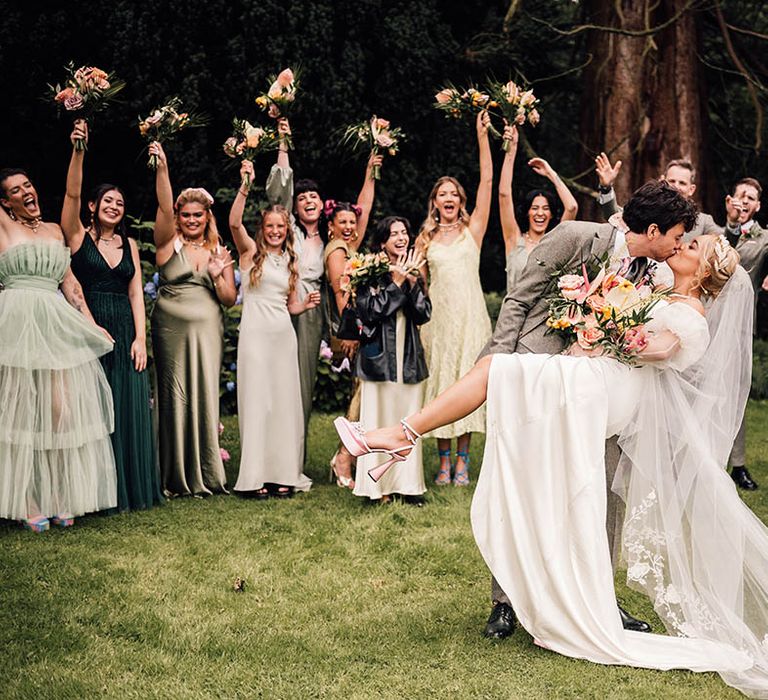 The bride and groom share a kiss in front of the wedding party 