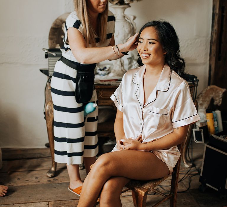 Bride in pink satin pyjamas getting her makeup done 