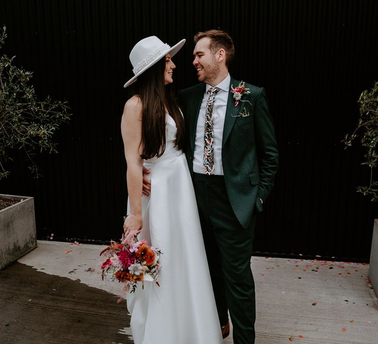 Bride wearing white pearl hat posing with groom at The Shack Revolution 