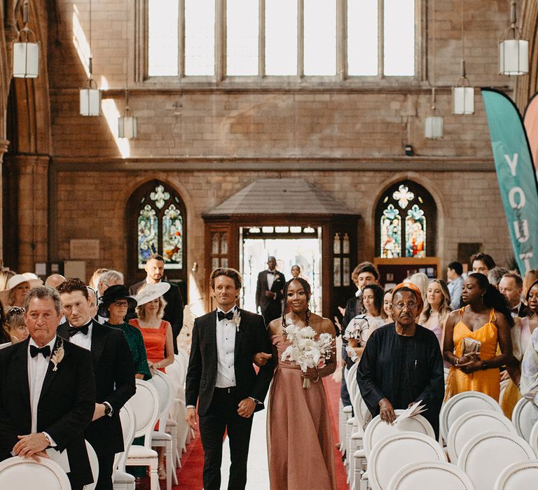 Bridesmaids and groomsmen walk down the aisle at wedding 