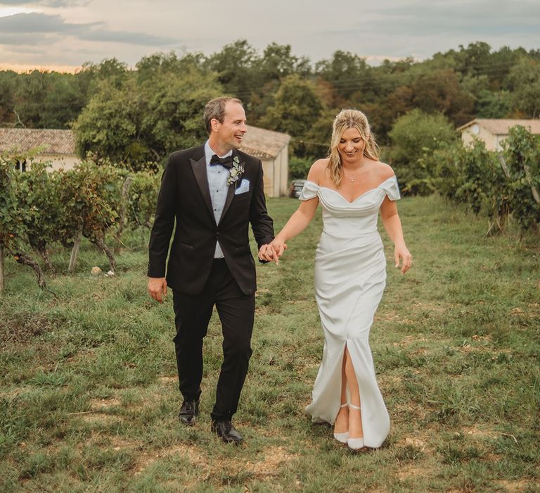 Bride in off the shoulder wedding dress with groom in black tuxedo cute couple portrait 