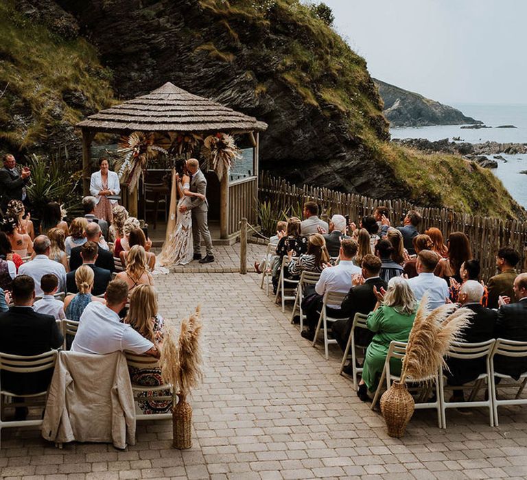 Tunnels Beaches wedding in Devon with outdoor ceremony area with guests seated 