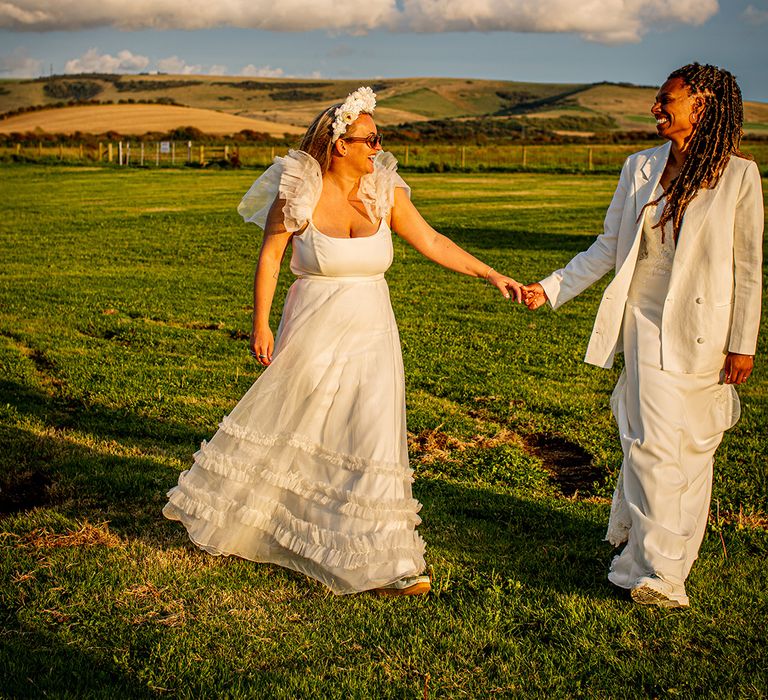 Brides walking hand in hand together for couple portraits during golden hour 