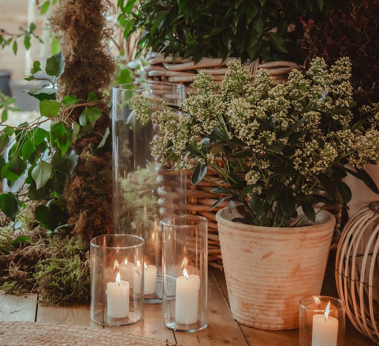 Candles in hurricane vases with plants from the polytunnel at the wedding venue 