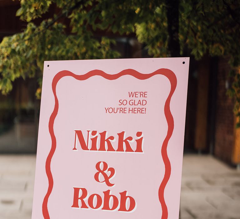 Red and pink wedding welcome sign with squiggle design 