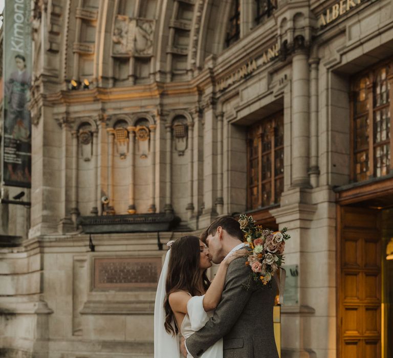 Bride and groom kissing outside their Holy Trinity Brompton Church wedding