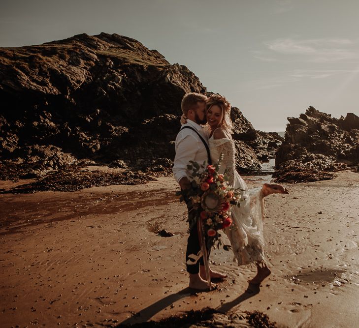 Bride and groom share a kiss on the sand of Anglesey Island 