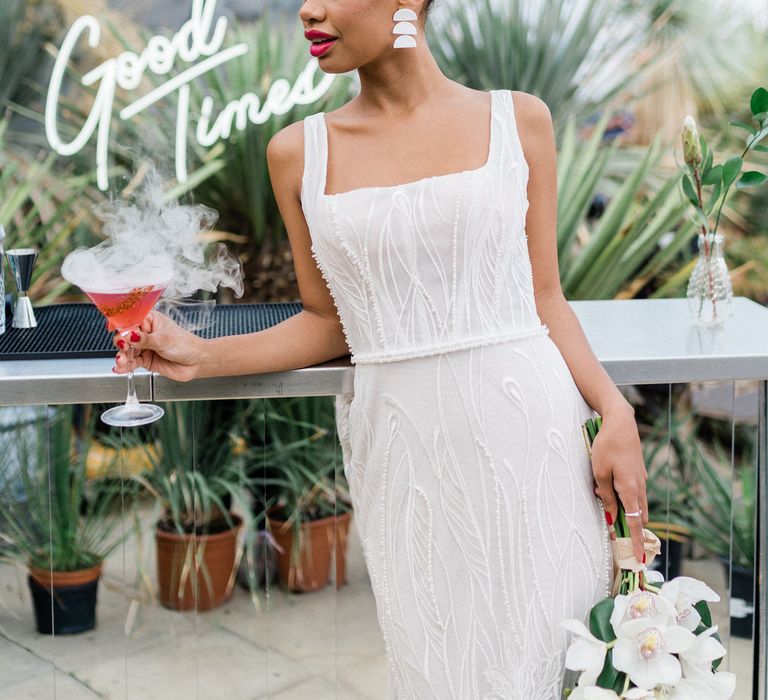 Bride in white Forrest by Rachel Rose Bridal dress holding red steaming cocktail and jungle themed bouquet at Urban Jungle Suffolk