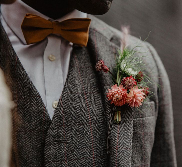 Close up of groom's tweed suit, buttonhole and mustard bow tie