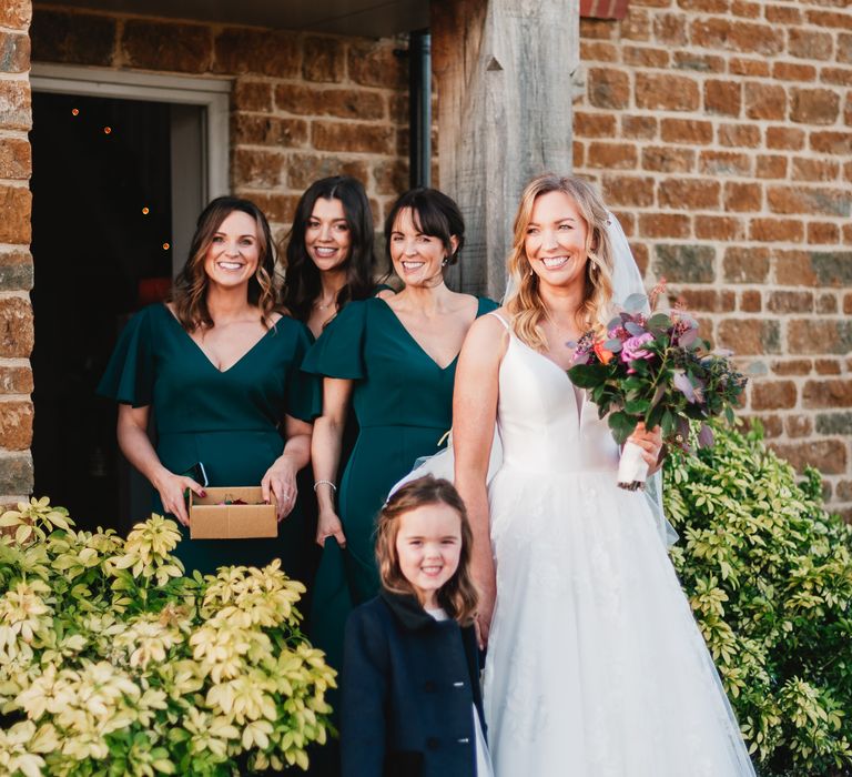 Bride stands with her bridesmaids in dark green dresses 