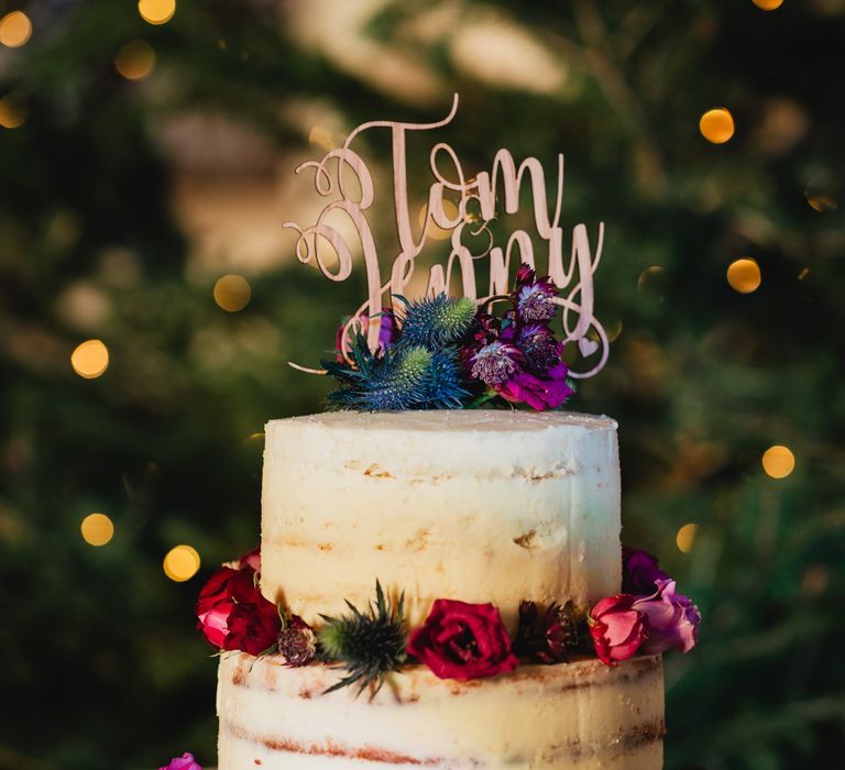 Naked cake with bright floral decoration and personalised names